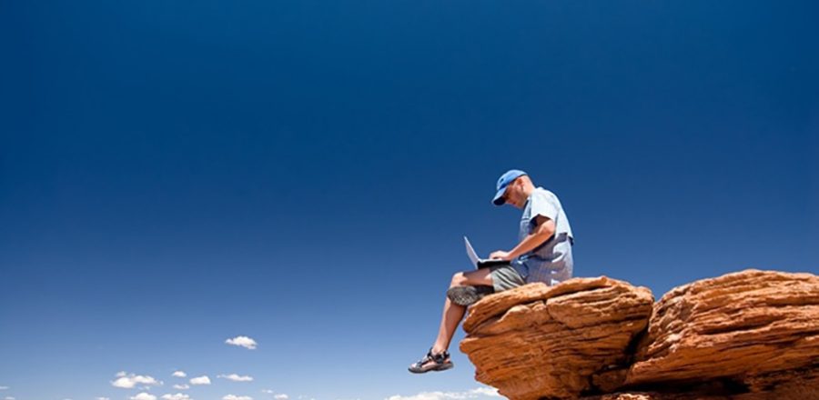 person working on a laptop atop a high mountain