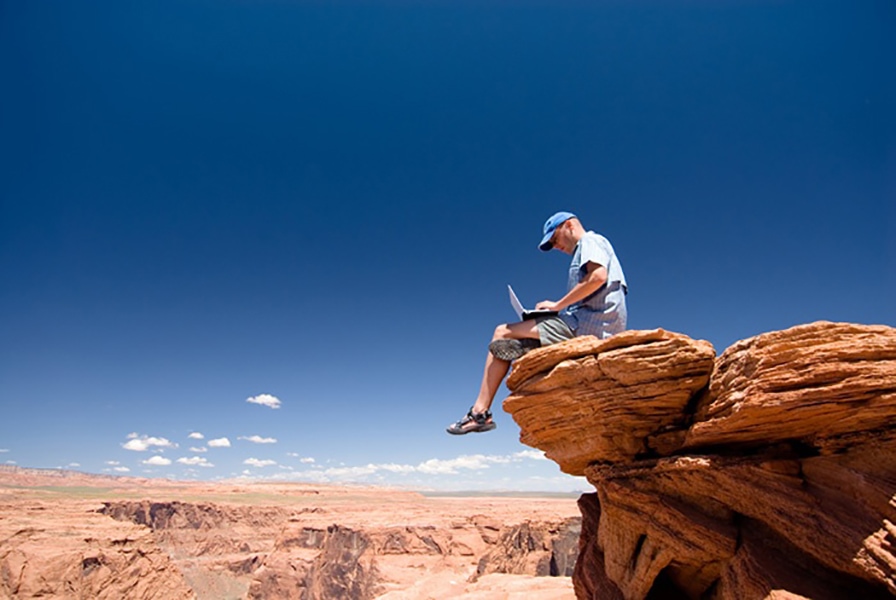 person working on a laptop atop a high mountain