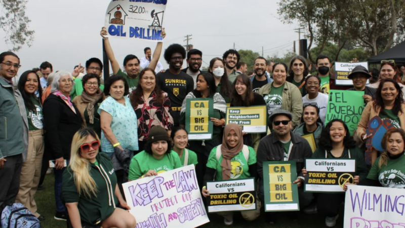 A large group of determined-looking protestors holding signs in English and Spanish that are protesting toxic oil drilling.