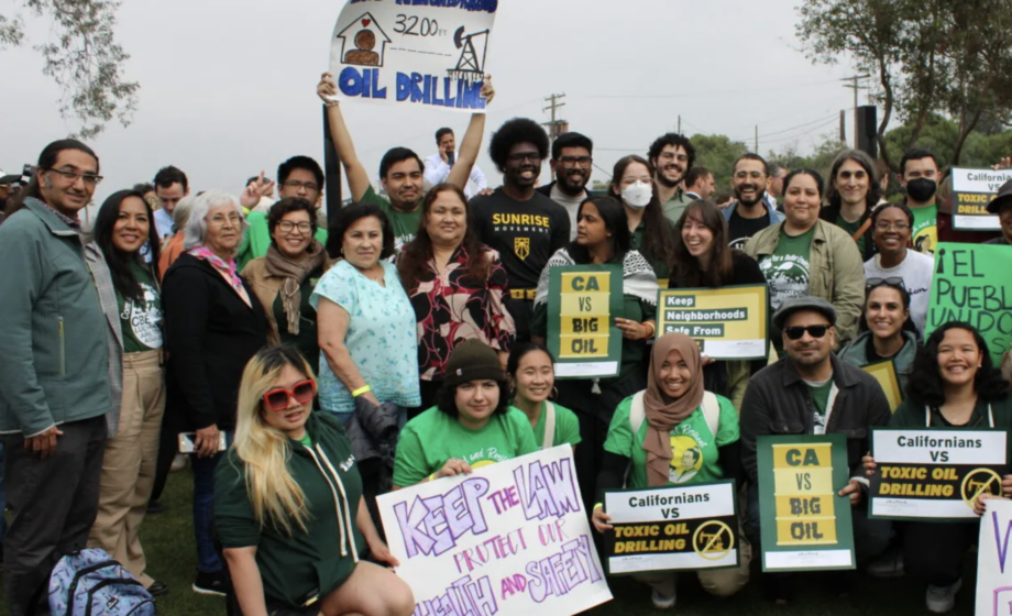 A large group of determined-looking protestors holding signs in English and Spanish that are protesting toxic oil drilling.